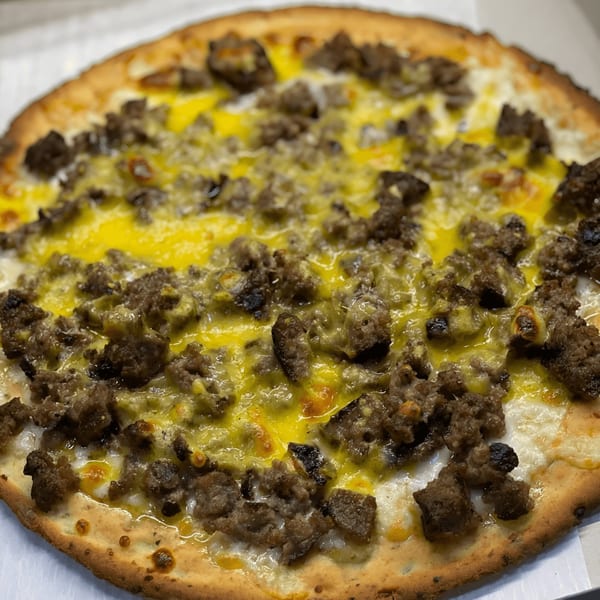 Catania's Pizza with crumbled sausage and melted yellow and white cheese.